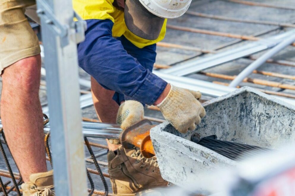Artisan du bâtiment attachant une entretoise à une barre d'armature au chantier de construction